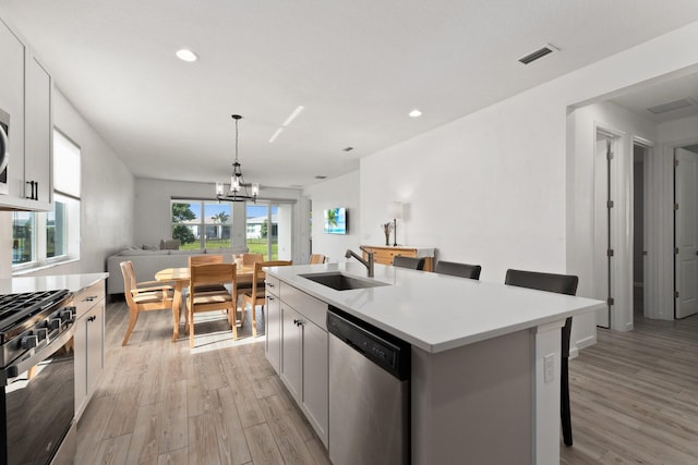 kitchen featuring visible vents, light wood-style flooring, a breakfast bar area, stainless steel appliances, and a sink