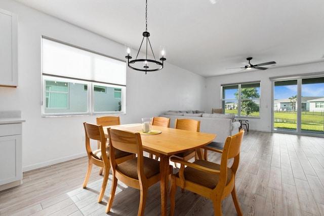 dining room featuring light wood-style flooring, baseboards, and ceiling fan with notable chandelier