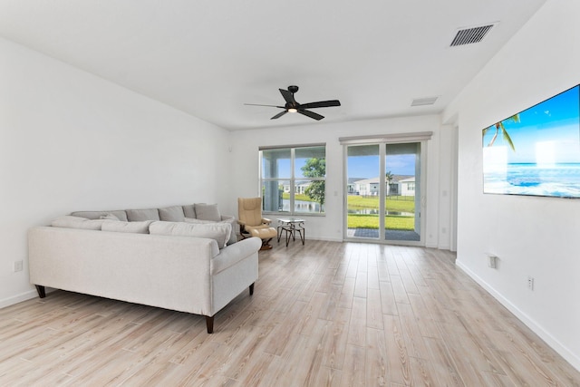 living area featuring light wood finished floors, a ceiling fan, visible vents, and baseboards