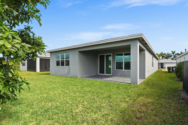 rear view of house featuring a yard, a patio, and stucco siding