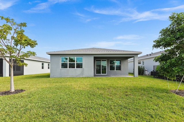 back of house featuring a lawn and stucco siding