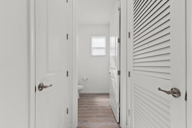 corridor featuring baseboards and light wood finished floors