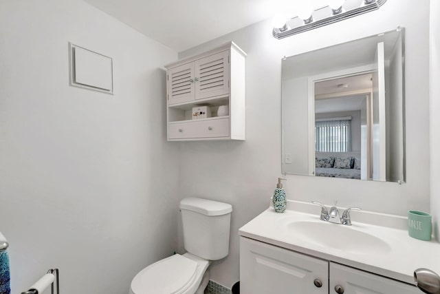 bathroom with toilet, connected bathroom, and vanity