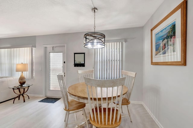 dining space featuring a notable chandelier, light wood-style flooring, and baseboards