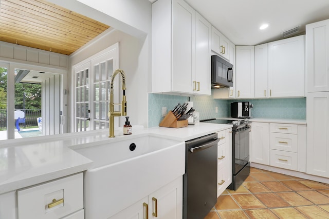 kitchen with a sink, white cabinets, light countertops, decorative backsplash, and black appliances