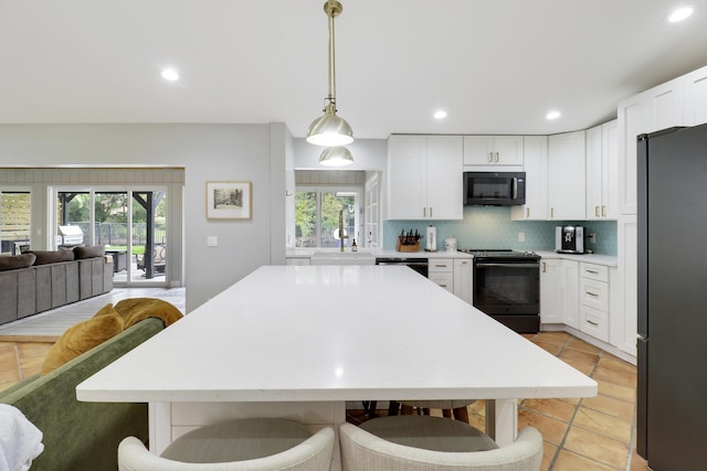 kitchen with tasteful backsplash, a sink, light countertops, black appliances, and a wealth of natural light