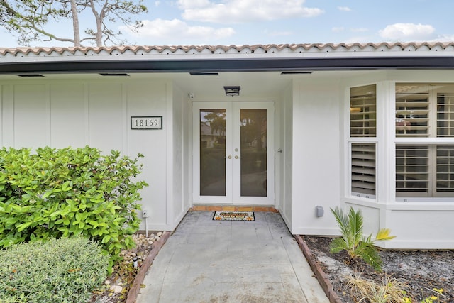 property entrance with stucco siding, a tiled roof, and french doors