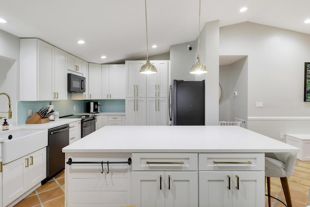 kitchen with black appliances, white cabinetry, vaulted ceiling, and a center island