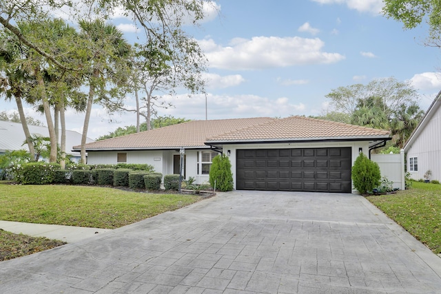 single story home featuring a garage, decorative driveway, a tiled roof, and a front lawn