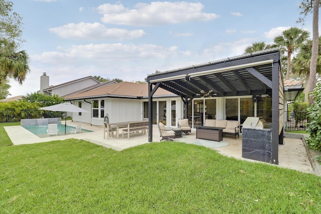 rear view of house featuring a patio area, a tile roof, an outdoor living space, and a yard