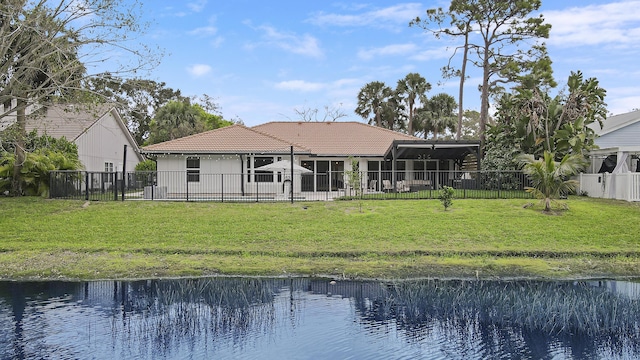 back of property with a yard, a fenced backyard, a water view, and a tiled roof