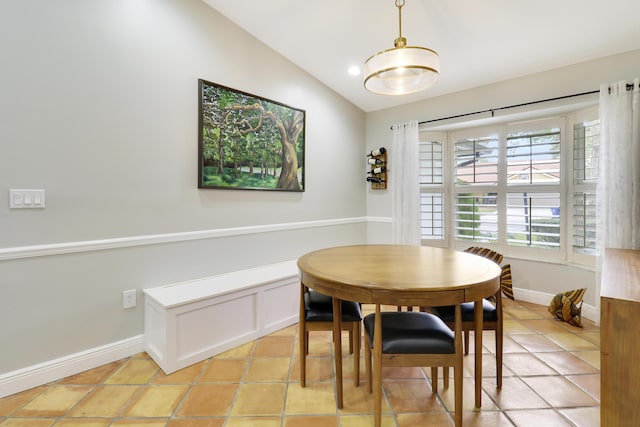 dining space with lofted ceiling, baseboards, and light tile patterned flooring