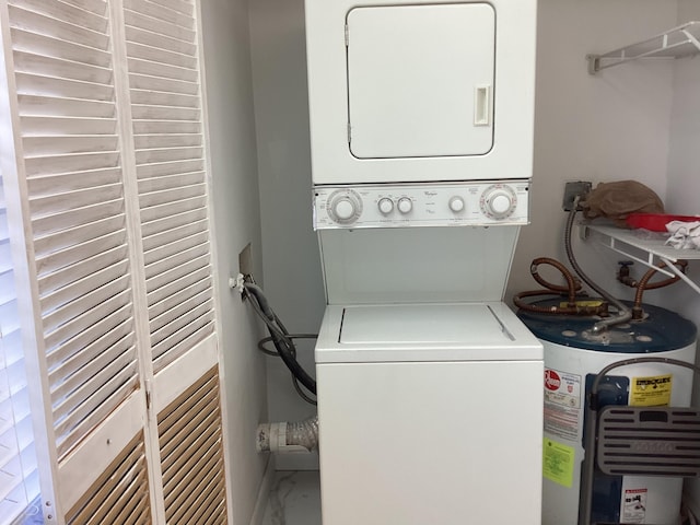 washroom featuring stacked washer and clothes dryer, electric water heater, marble finish floor, and laundry area