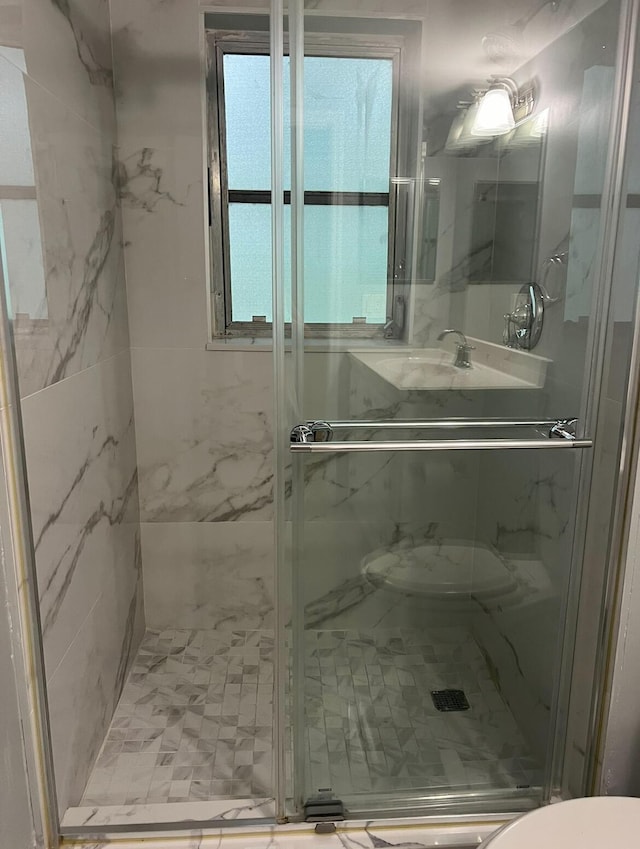 bathroom with toilet and a marble finish shower