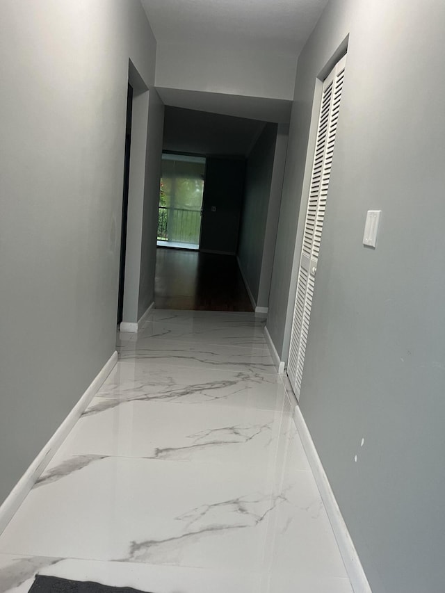 hall with marble finish floor and baseboards