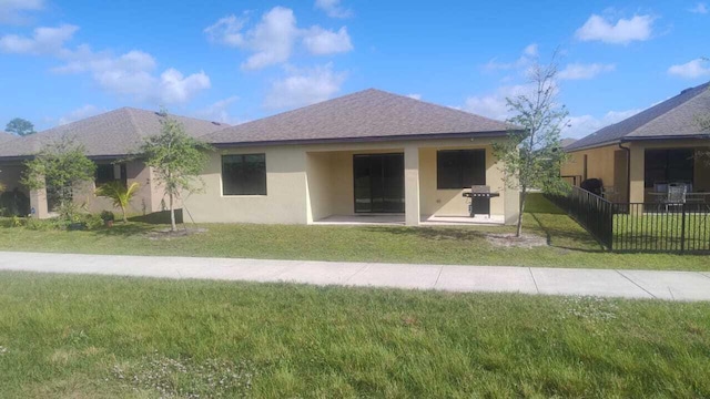 6259 NW Regent St, Port Saint Lucie, FL 34983 - rear view of house featuring a lawn, fence, stucco siding, and roof with shingles