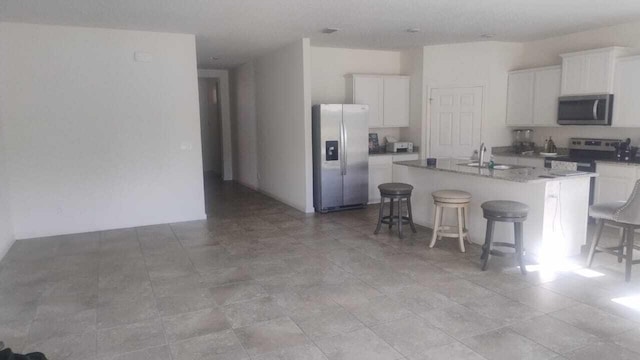 6259 NW Regent St, Port Saint Lucie, FL 34983 - kitchen featuring a kitchen breakfast bar, a center island with sink, white cabinetry, a sink, and stainless steel appliances