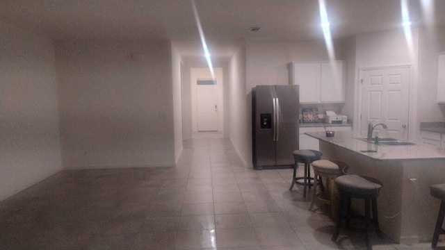 6259 NW Regent St, Port Saint Lucie, FL 34983 - kitchen featuring a kitchen breakfast bar, stainless steel fridge, light countertops, white cabinets, and a sink