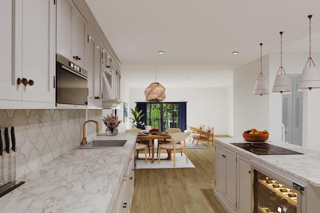 kitchen featuring beverage cooler, black electric stovetop, decorative light fixtures, and light wood-style floors