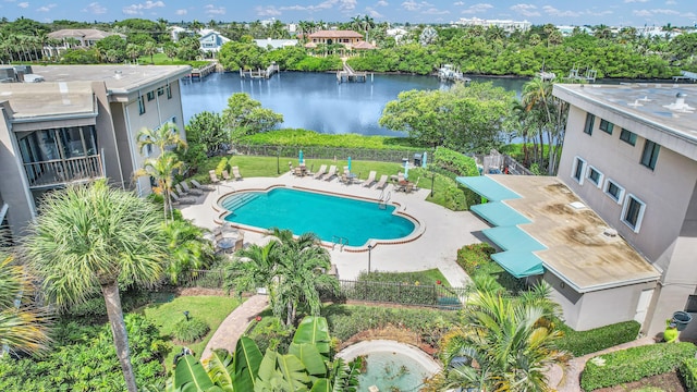 community pool with a patio area, fence, and a water view