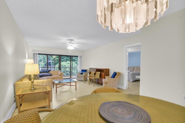 living area featuring baseboards and ceiling fan with notable chandelier