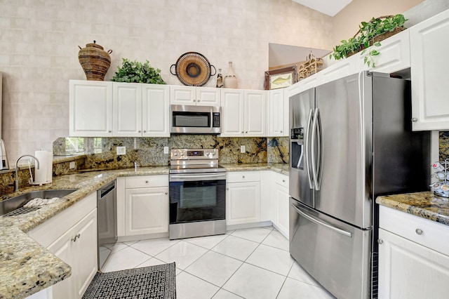 kitchen with light tile patterned floors, light stone counters, stainless steel appliances, a sink, and decorative backsplash