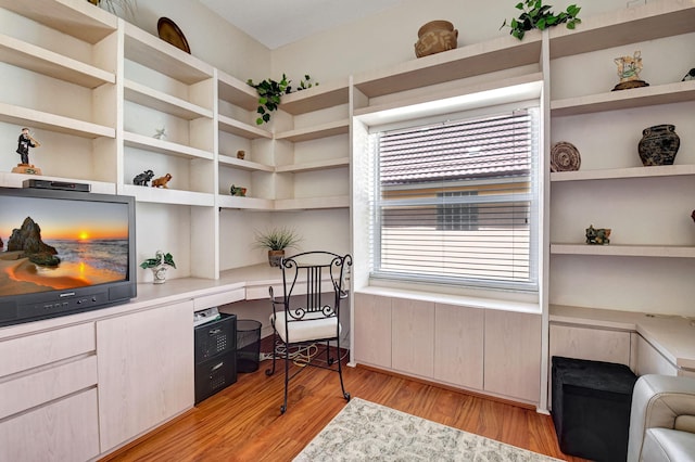 office space featuring built in shelves, light wood-type flooring, and built in desk