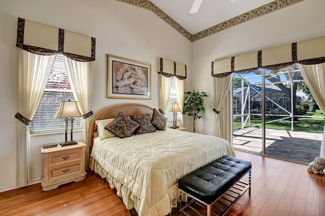 bedroom featuring access to outside, light wood finished floors, multiple windows, and a sunroom