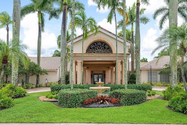 exterior space with stucco siding, a tiled roof, and a yard