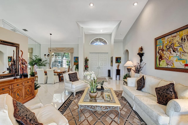 living area with light tile patterned floors, arched walkways, recessed lighting, visible vents, and an inviting chandelier