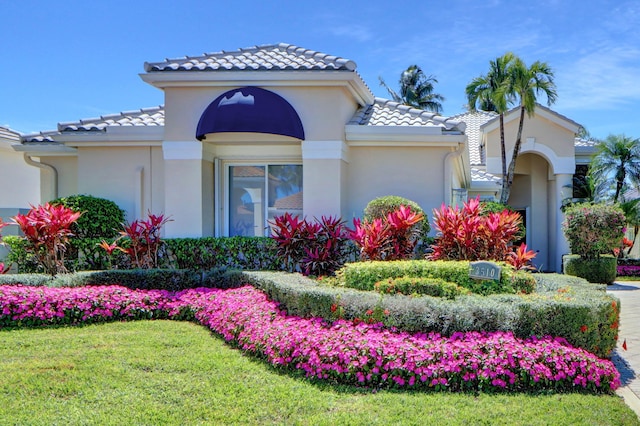 mediterranean / spanish-style house featuring stucco siding, a front lawn, and a tiled roof