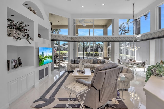 tiled living room with recessed lighting, a high ceiling, and ceiling fan with notable chandelier