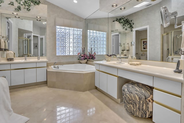 bathroom featuring a garden tub, two vanities, a stall shower, and a sink