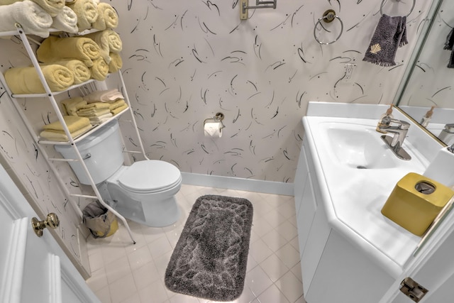 bathroom with vanity, baseboards, wallpapered walls, tile patterned flooring, and toilet