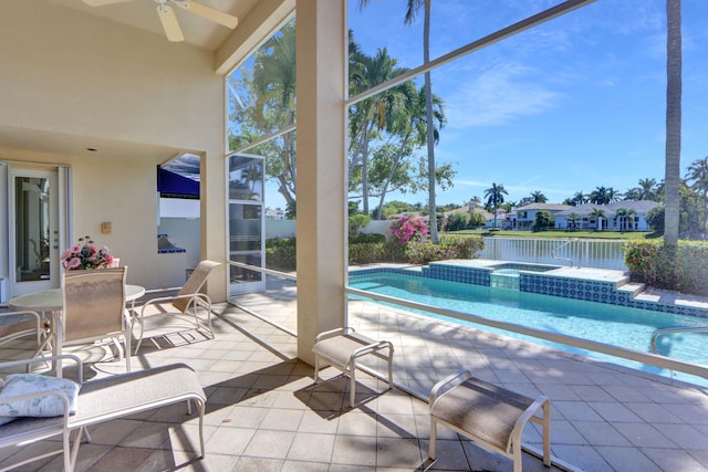 view of pool with glass enclosure, a pool with connected hot tub, a ceiling fan, and a patio area