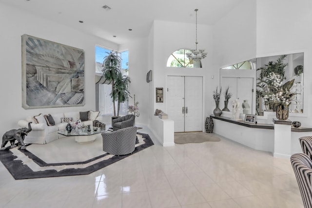 foyer with an inviting chandelier, tile patterned floors, visible vents, and a towering ceiling