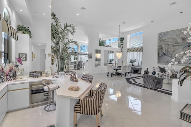 interior space with visible vents, a breakfast bar area, light countertops, light tile patterned floors, and white cabinetry