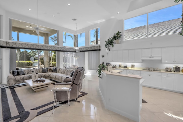 living area with light tile patterned flooring, recessed lighting, a towering ceiling, and ceiling fan