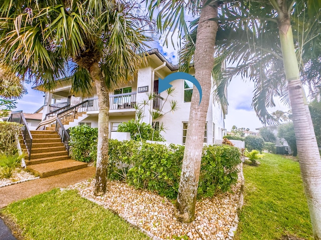 view of side of home featuring stairs, a lawn, and stucco siding