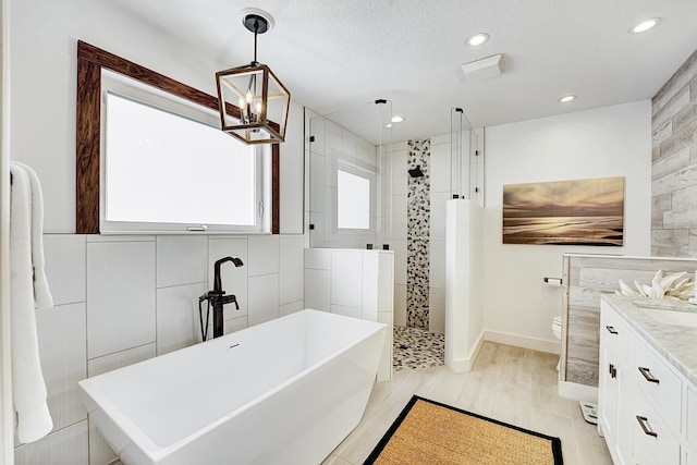 full bathroom featuring toilet, vanity, tile walls, a freestanding bath, and walk in shower