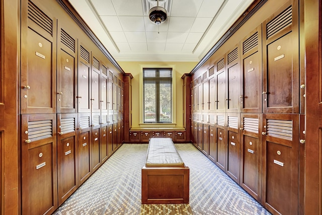 mudroom with mail area, crown molding, and light colored carpet