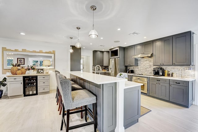 kitchen featuring tasteful backsplash, visible vents, gray cabinetry, appliances with stainless steel finishes, and beverage cooler