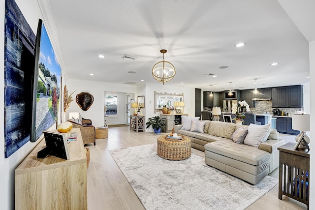 living room featuring light wood-style flooring, recessed lighting, crown molding, visible vents, and an inviting chandelier