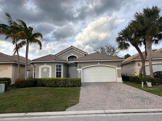 mediterranean / spanish-style home with a garage, a front lawn, decorative driveway, and stucco siding