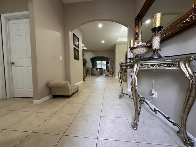 hall with arched walkways, recessed lighting, tile patterned flooring, and baseboards