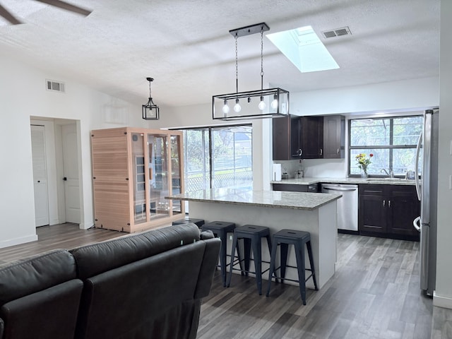 kitchen with vaulted ceiling with skylight, visible vents, stainless steel appliances, and a sink