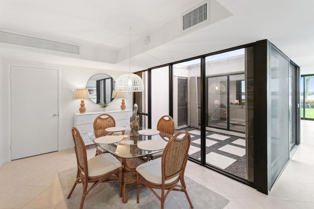 dining room featuring light tile patterned floors, visible vents, a wall of windows, and a tray ceiling