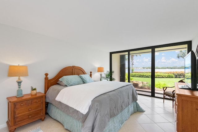 bedroom with access to exterior, expansive windows, and light tile patterned floors