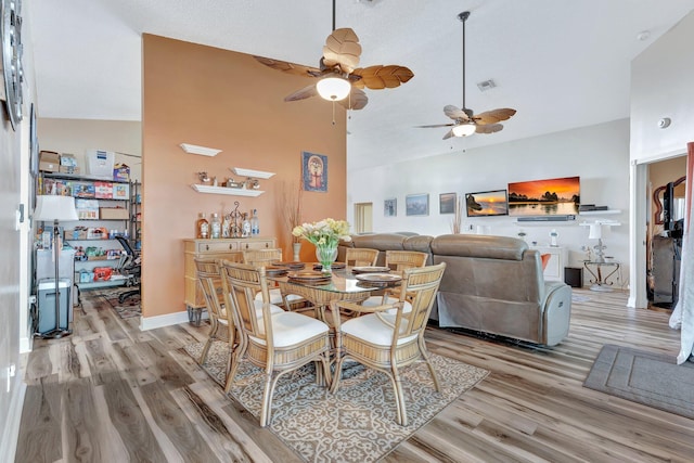 dining space with light wood-style floors, visible vents, high vaulted ceiling, and baseboards