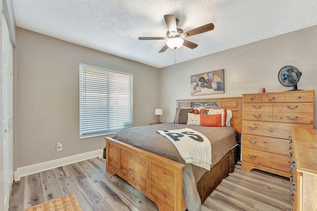 bedroom featuring a textured ceiling, a ceiling fan, light wood-style flooring, and baseboards